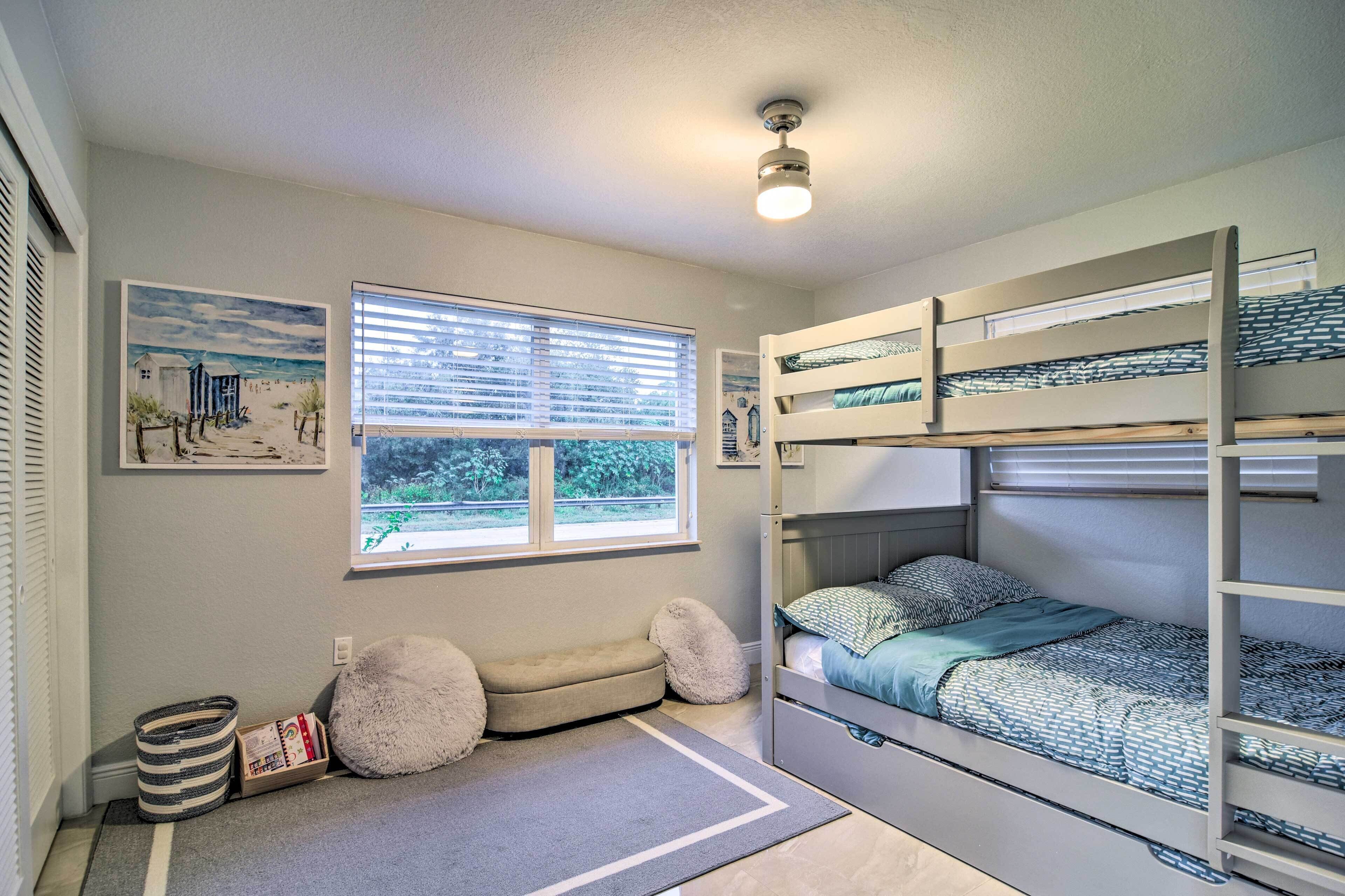 Une chambre avec un lit superposé, une fenêtre, un tableau et un petit coin salon.
