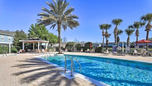 Une piscine avec un palmier et des chaises longues.