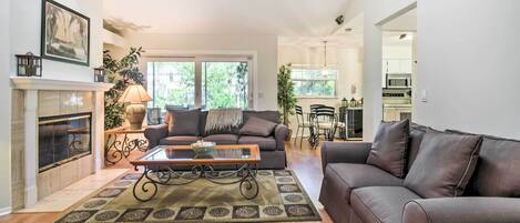 A living room with a fireplace, a sofa, a coffee table, and a dining area with a chandelier.