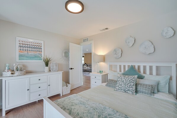 Une chambre à coucher comprenant un lit, des tables de chevet, une commode, un miroir et des éléments décoratifs sur les murs.