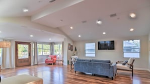 A spacious living room with hardwood floors, a grey sofa, and a red armchair. - Vibrant Dunedin Getaway w/ Furnished Patio! (Dunedin)