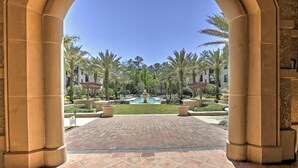 A courtyard with a pool, palm trees, and a view of a building.