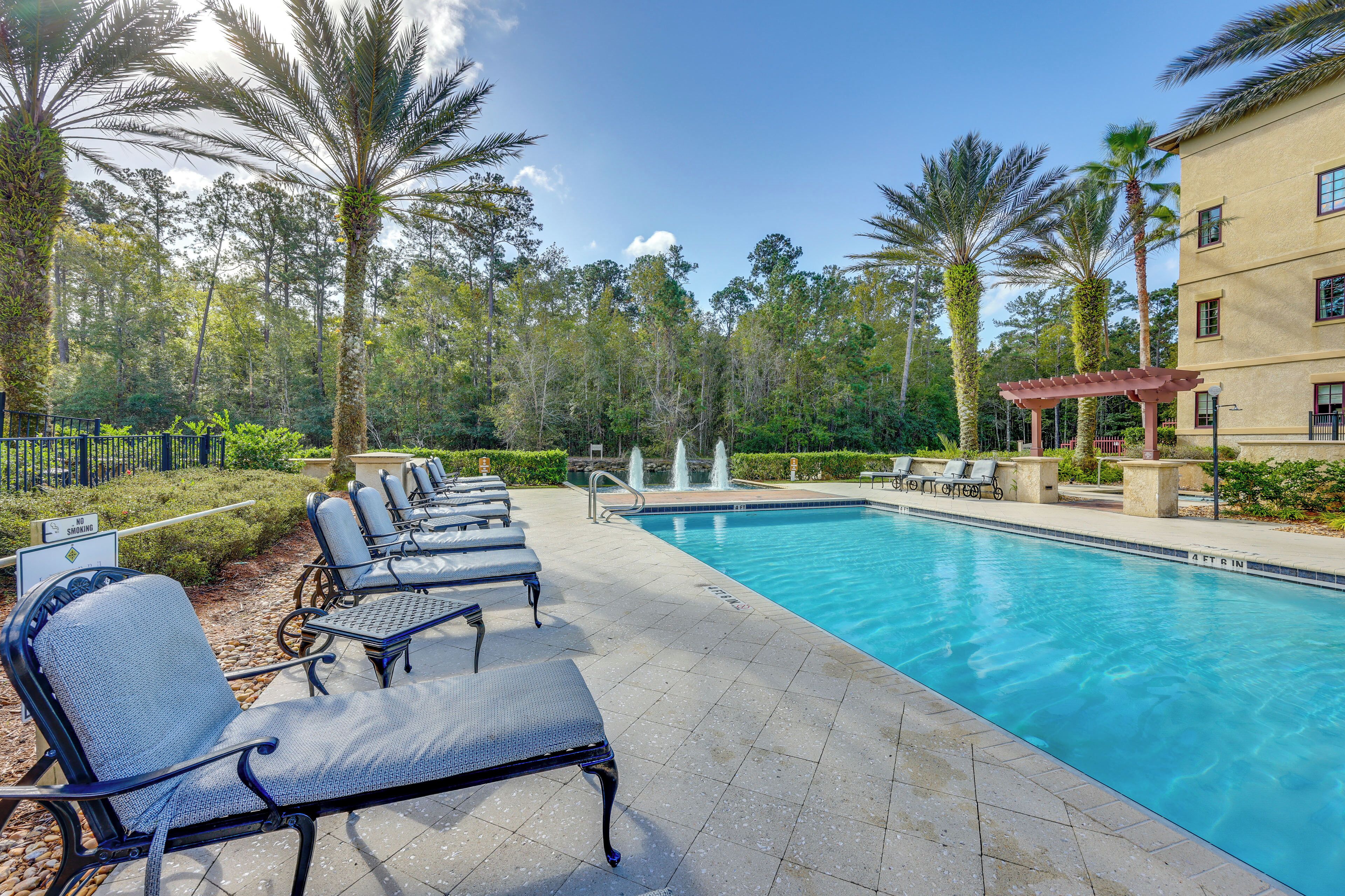 A pool area with lounge chairs and a building in the background.