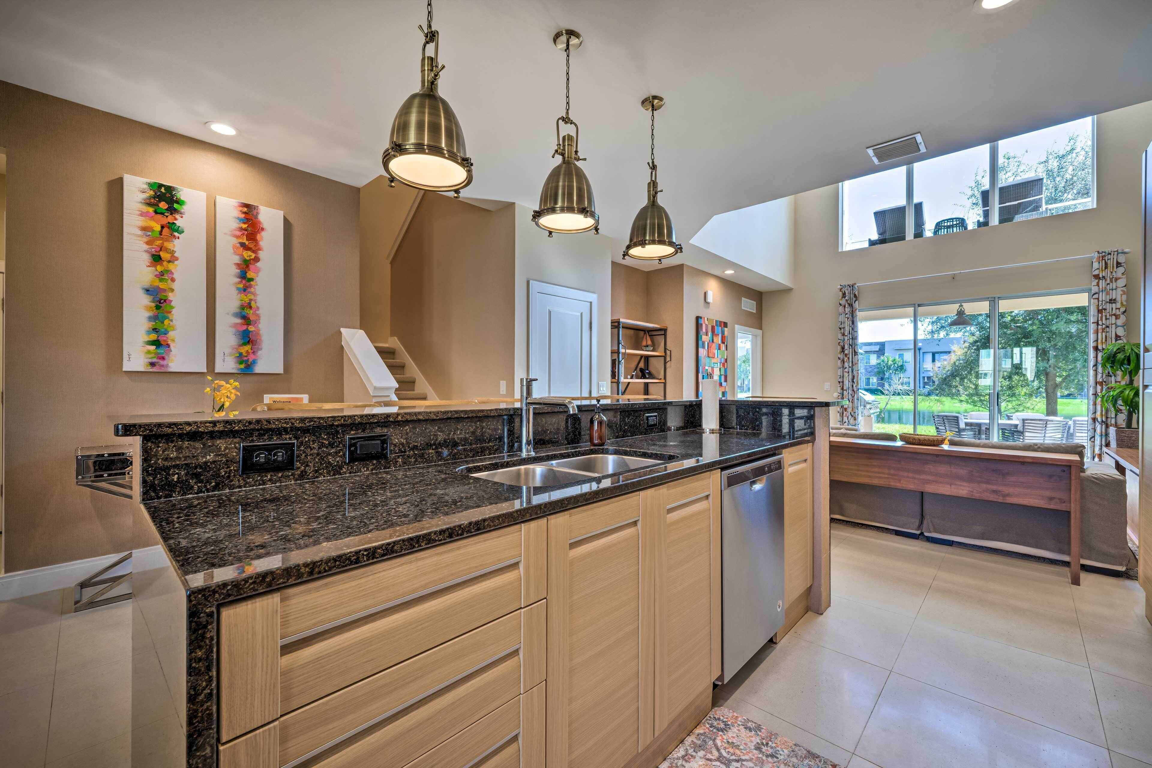 Una cocina moderna con encimeras de granito, gabinetes de madera e iluminación colgante.