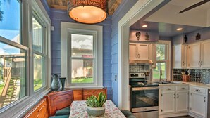 A kitchen with white cabinets, a built-in oven, and a window overlooking a backyard.