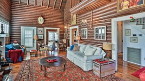 A log cabin interior with a cozy living room, wooden ceiling, and rustic decor.