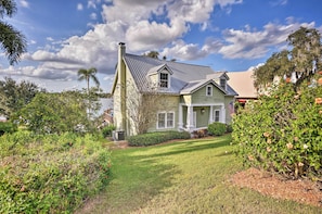 A house with a green roof, white trim, and a front porch. There is a lawn in front of the house and a tree to the left.