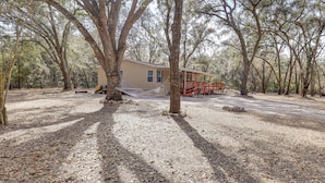 A cabin surrounded by trees with a gravel path leading to it.