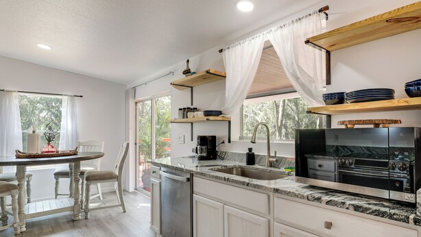 A modern kitchen with a built-in dishwasher, a large island with seating, and a black stove.