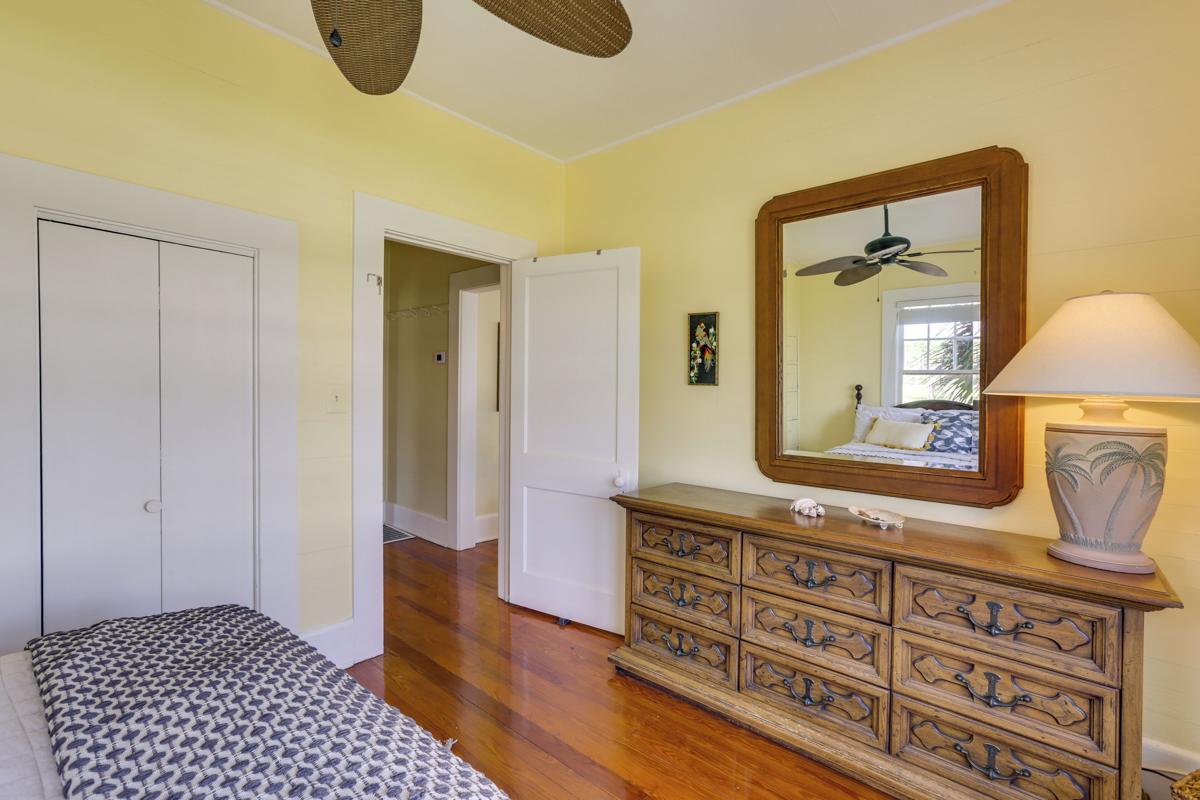 A bedroom with a bed, a dresser, a mirror, and a ceiling fan.