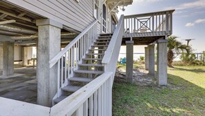 Ein zweistöckiges Haus mit einer Holzterrasse und einer Treppe, die zu einem Balkon führt.