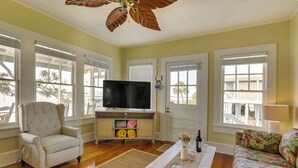 Ein Wohnzimmer mit Fernseher, Sessel, Sofa und Deckenventilator.