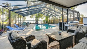 A covered outdoor area with a pool, lounge chairs, and a grill. - Dock & Beautiful Views! Spacious Bellows Lake Gem (Tampa)