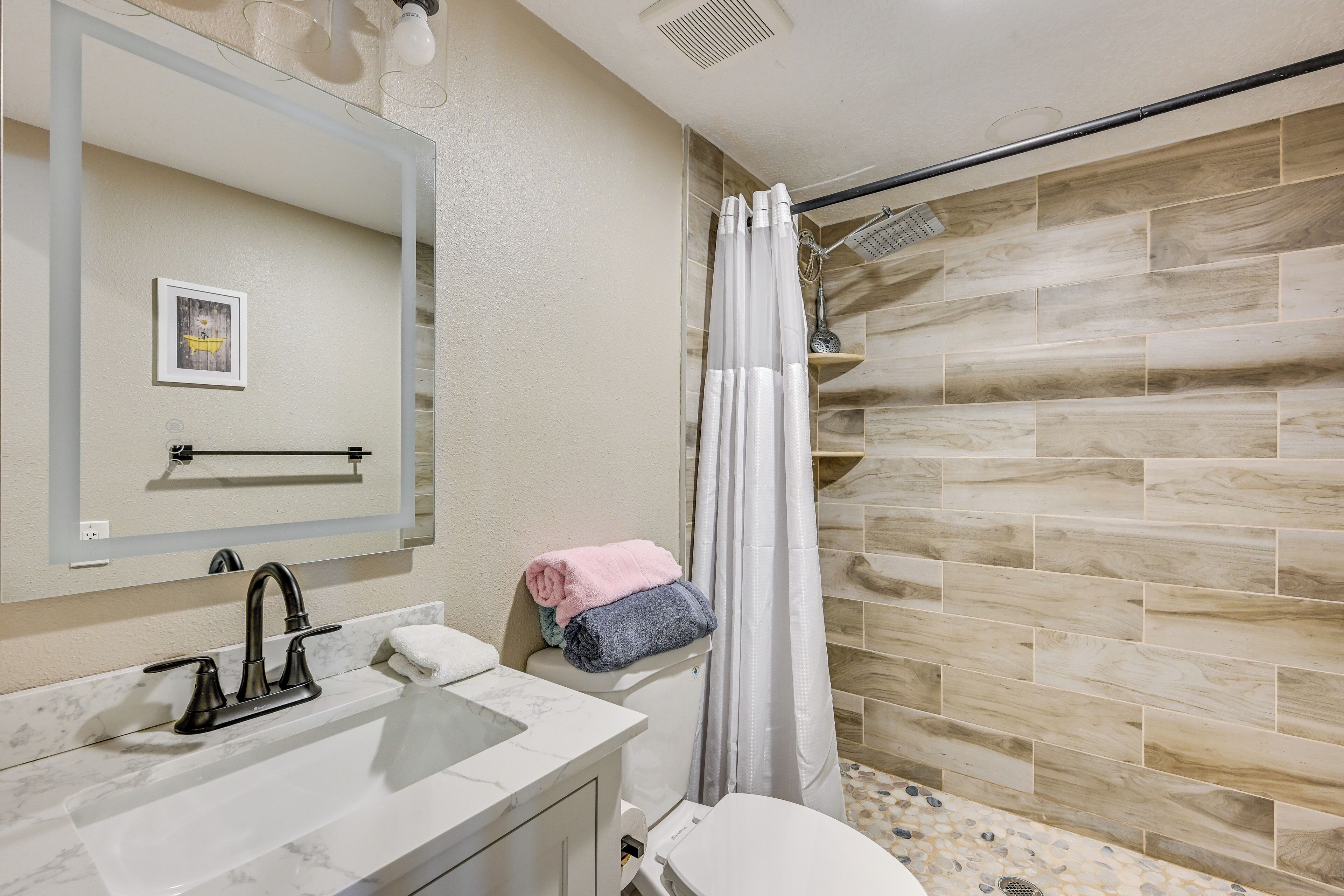 Une salle de bain avec un lavabo en marbre, des toilettes et une douche avec un mur en bois.