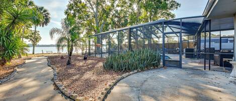A covered outdoor area with a curved pathway, surrounded by trees and a view of the water.