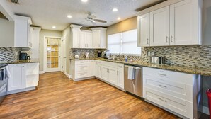 A modern kitchen with white cabinets, a wooden floor, and a tiled backsplash. - Dock & Beautiful Views! Spacious Bellows Lake Gem (Tampa)