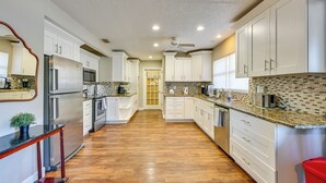 A modern kitchen with white cabinets, stainless steel appliances, and a wooden floor. - Dock & Beautiful Views! Spacious Bellows Lake Gem (Tampa)