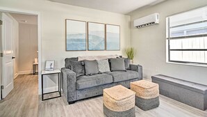 A modern living room with a grey sofa, two woven ottomans, a small side table, and a ceiling fan. - Well-appointed Madeira Beach Condo w/ Patio! (Madeira Beach)