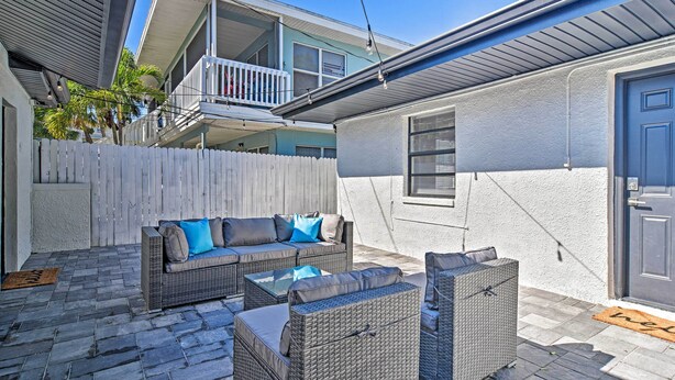 A patio area with wicker furniture, a white picket fence, and a balcony. - Well-appointed Madeira Beach Condo w/ Patio! (Madeira Beach)