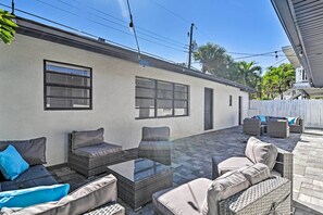 An outdoor patio with wicker furniture, a glass-top table, and a white wall with windows. - Well-appointed Madeira Beach Condo w/ Patio! (Madeira Beach)