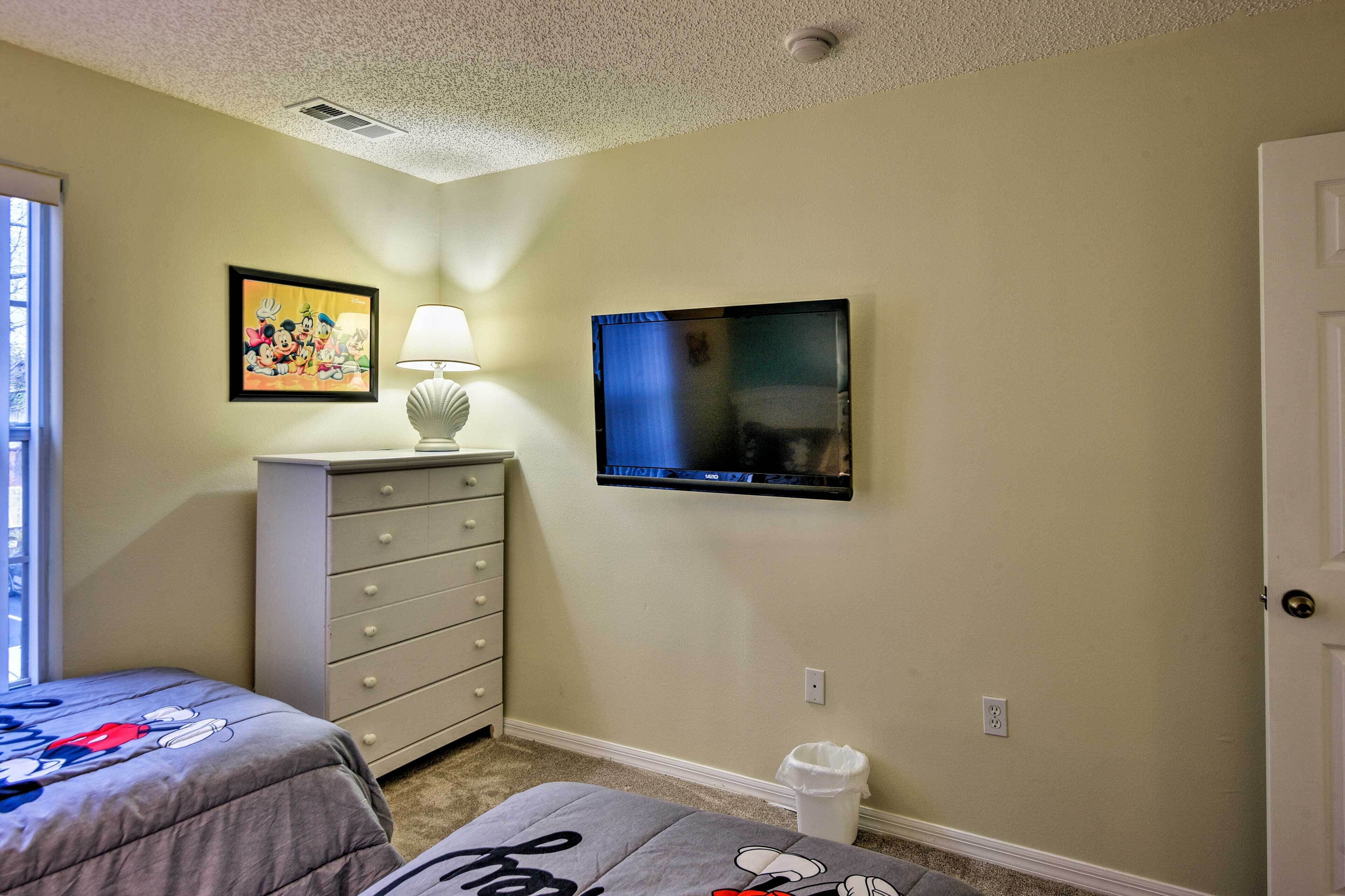 A bedroom with a bed, dresser, TV, and a picture on the wall.