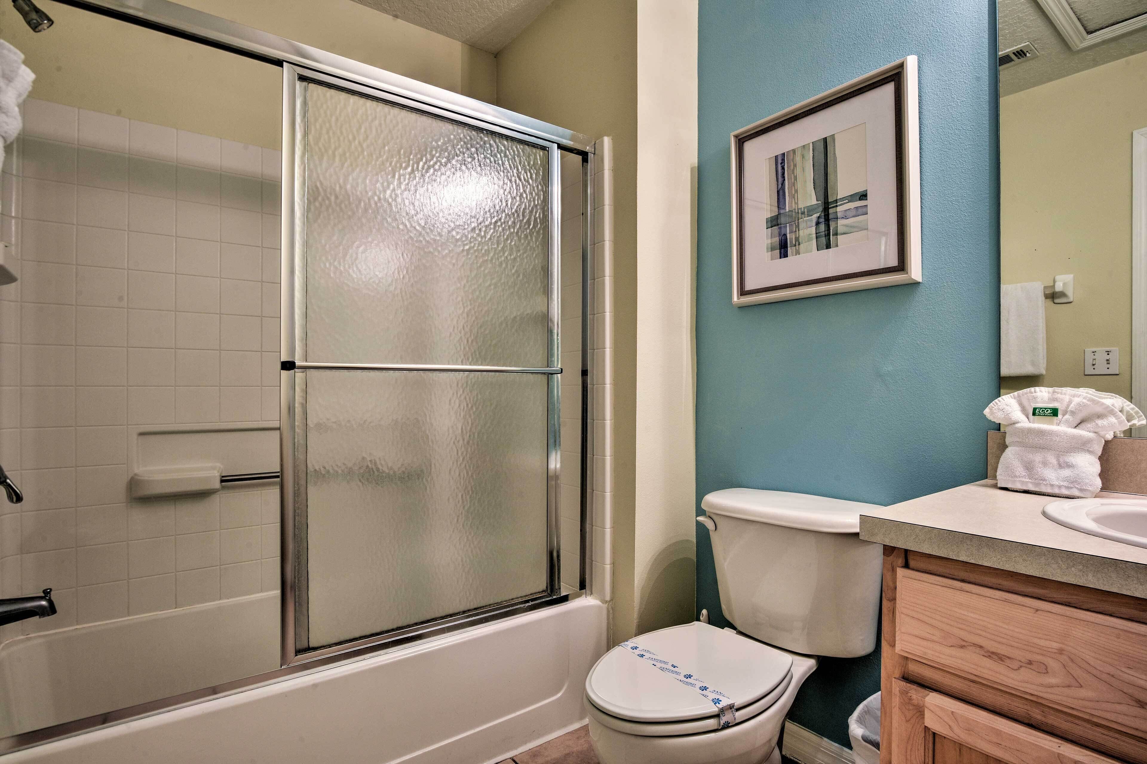 A bathroom with a glass-enclosed shower, a white toilet, and a sink with a wooden vanity.