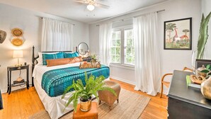 A bedroom with a bed, a ceiling fan, a nightstand, a chair, a window with curtains, and a framed picture on the wall. - ~ 12 Mi to Disney: Downtown Winter Garden Cottage! (Winter Garden)
