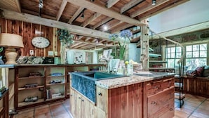 A rustic kitchen with wooden beams, a built-in island with a sink, and a clock on the wall.