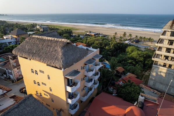A multi-story building with balconies overlooking a beach.