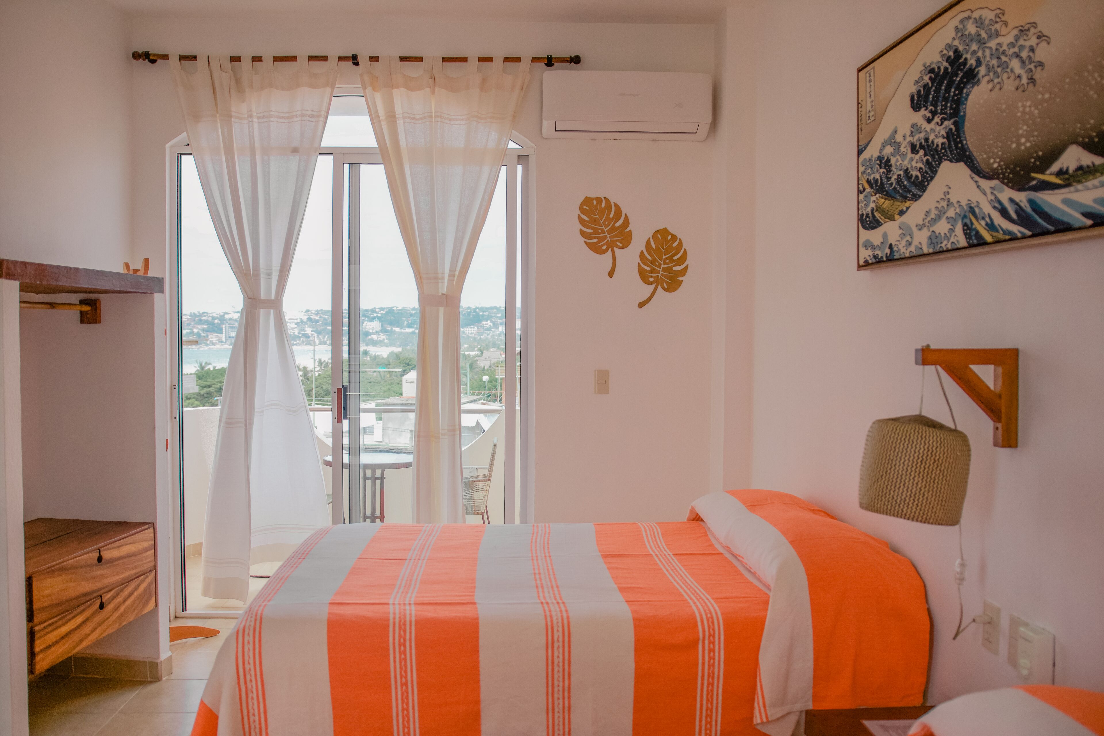 Une chambre à coucher avec un lit, une fenêtre avec des rideaux, un climatiseur fixé au mur et un tableau.