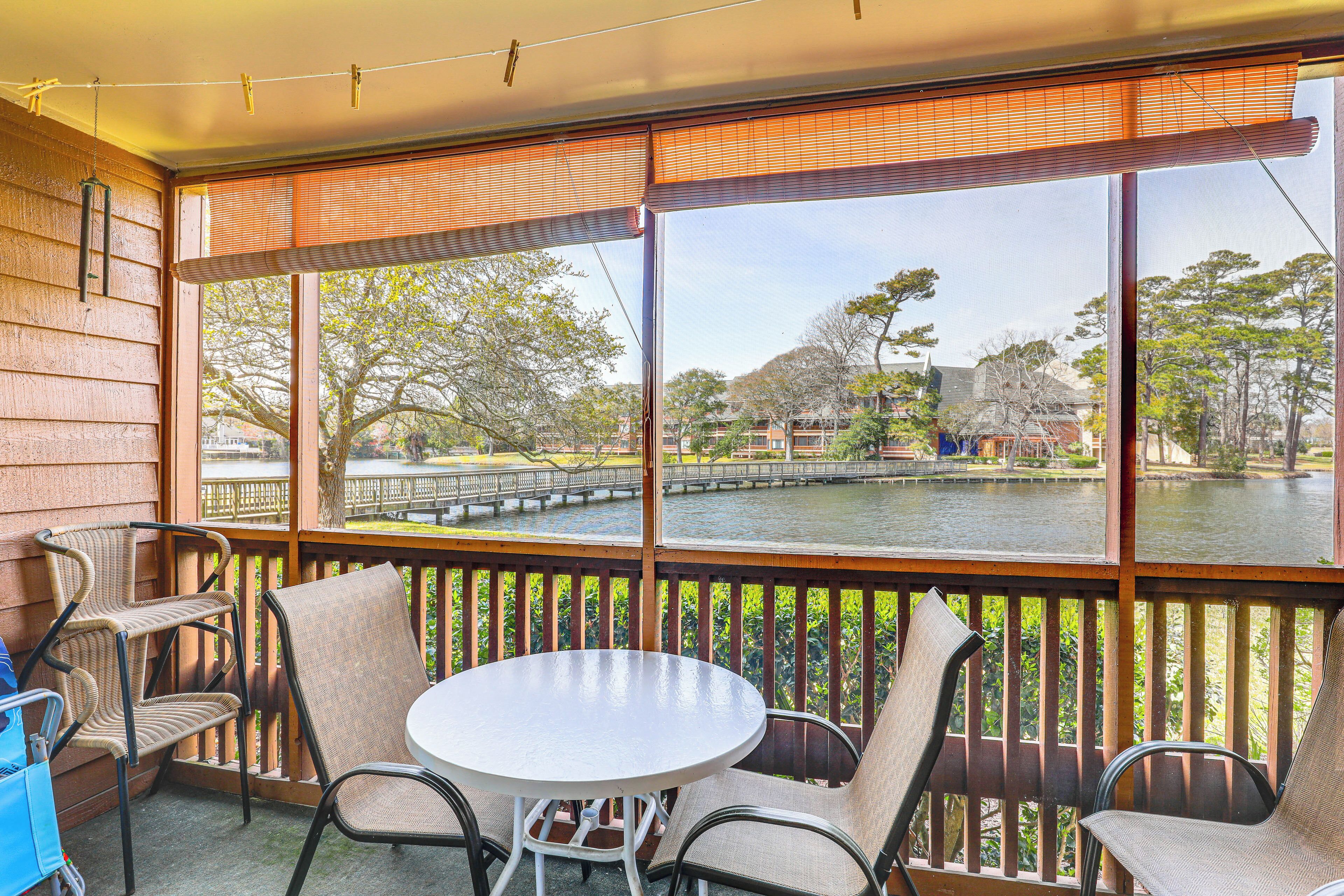 A balcony with a view of a river, wooden railing, and outdoor furniture.