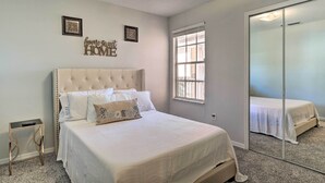 Une chambre à coucher avec un grand lit, une table de chevet, un miroir et une fenêtre.
