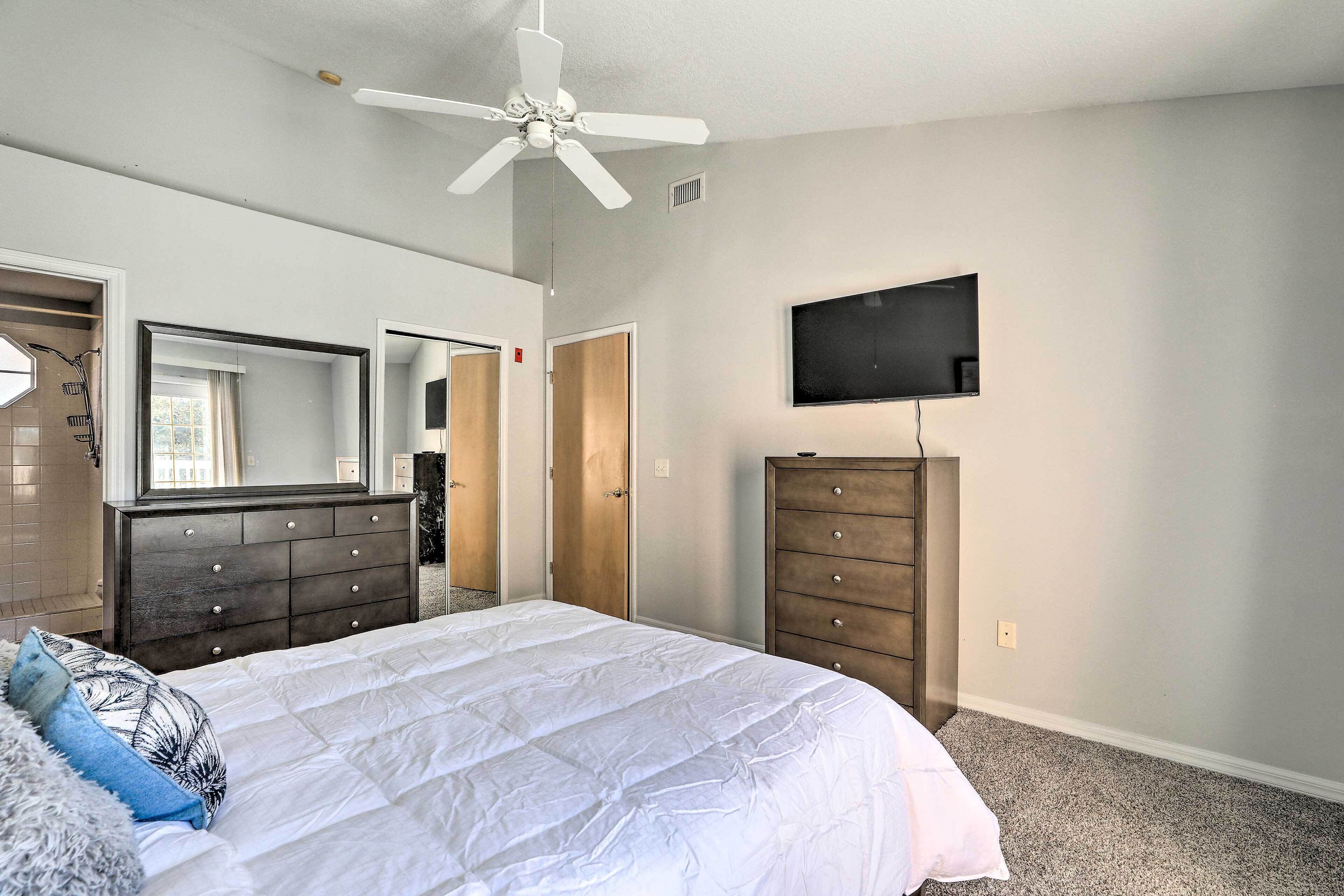 A bedroom with a bed, a dresser, a TV, and a ceiling fan.