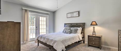 A bedroom with a bed, a nightstand, a ceiling fan, and a window with curtains.