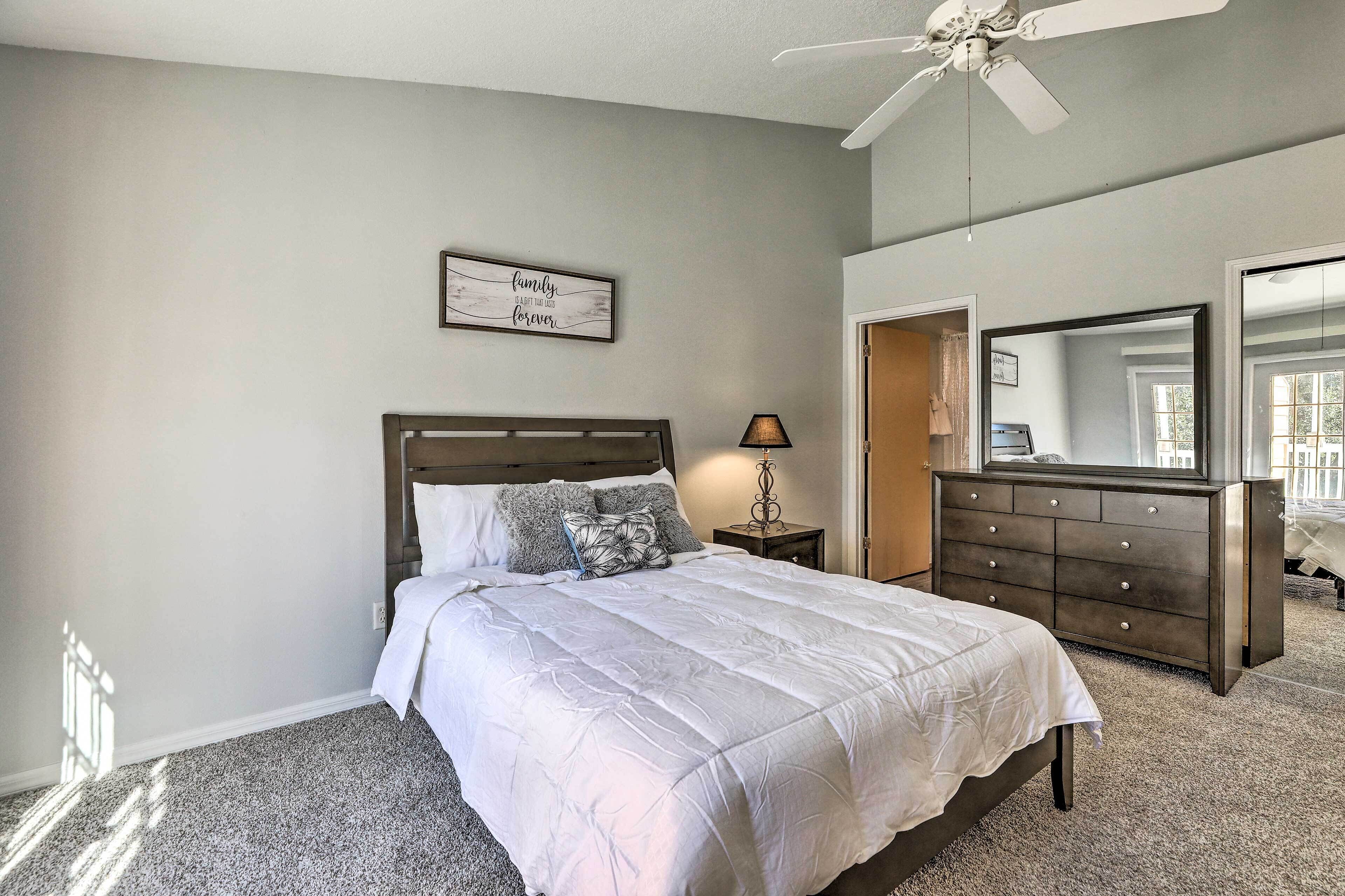 A bedroom with a bed, dresser, and a ceiling fan.
