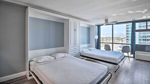 A modern hotel room with two beds, a large wardrobe, and a balcony with a city view. - Beachfront Daytona Studio, Close to Parks! (Daytona Beach Shores)
