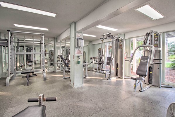 A gym with various exercise machines, mirrors, and a bench. - Beachfront Condo w/ 3 Pools on St Helena Island! (Harbor Island)