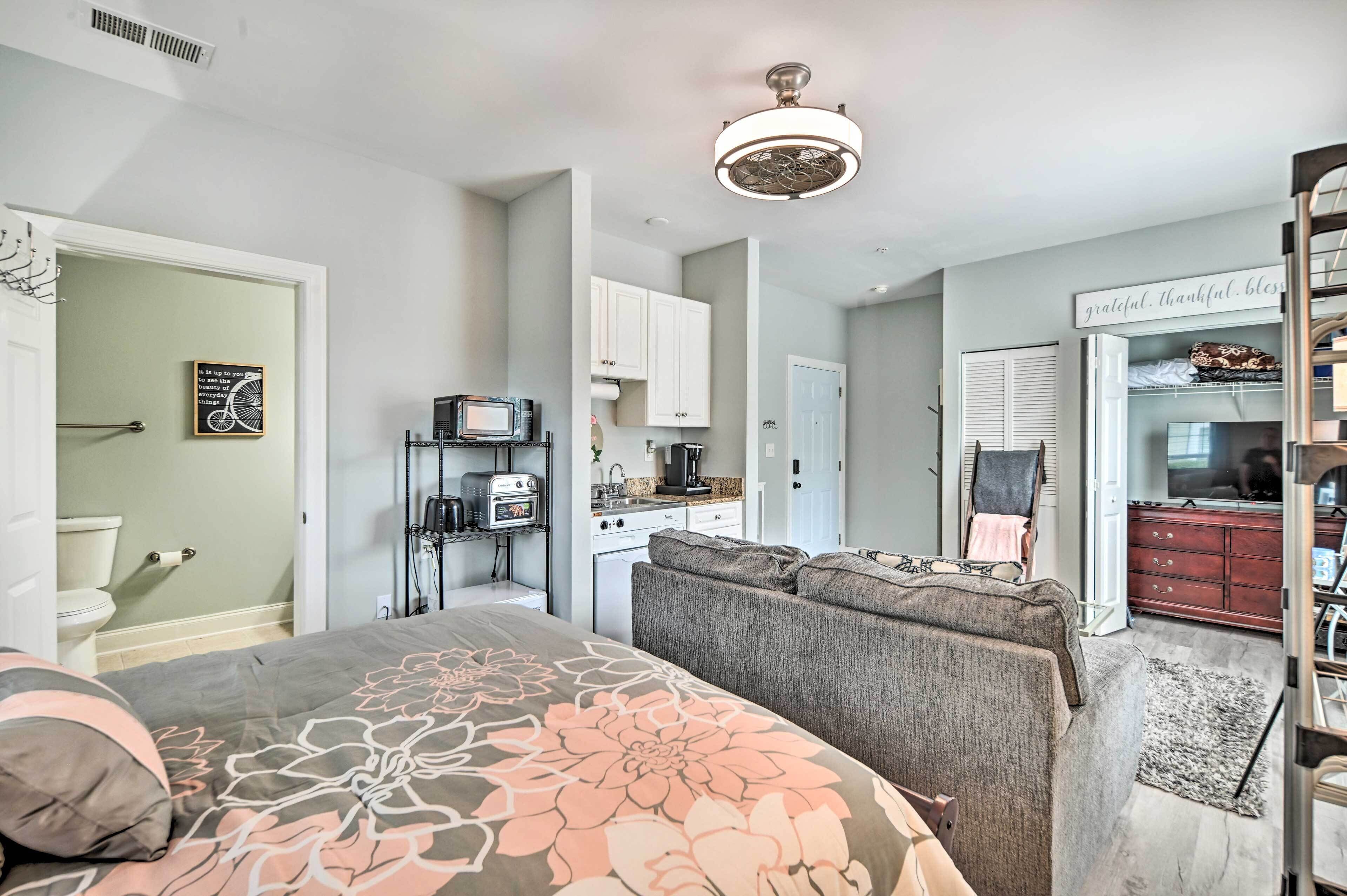 A compact living space with a bed, kitchenette, and a seating area.