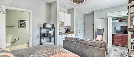A compact living space with a bed, kitchenette, and a seating area.