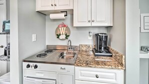 A compact kitchen with a stove, sink, and granite countertop.