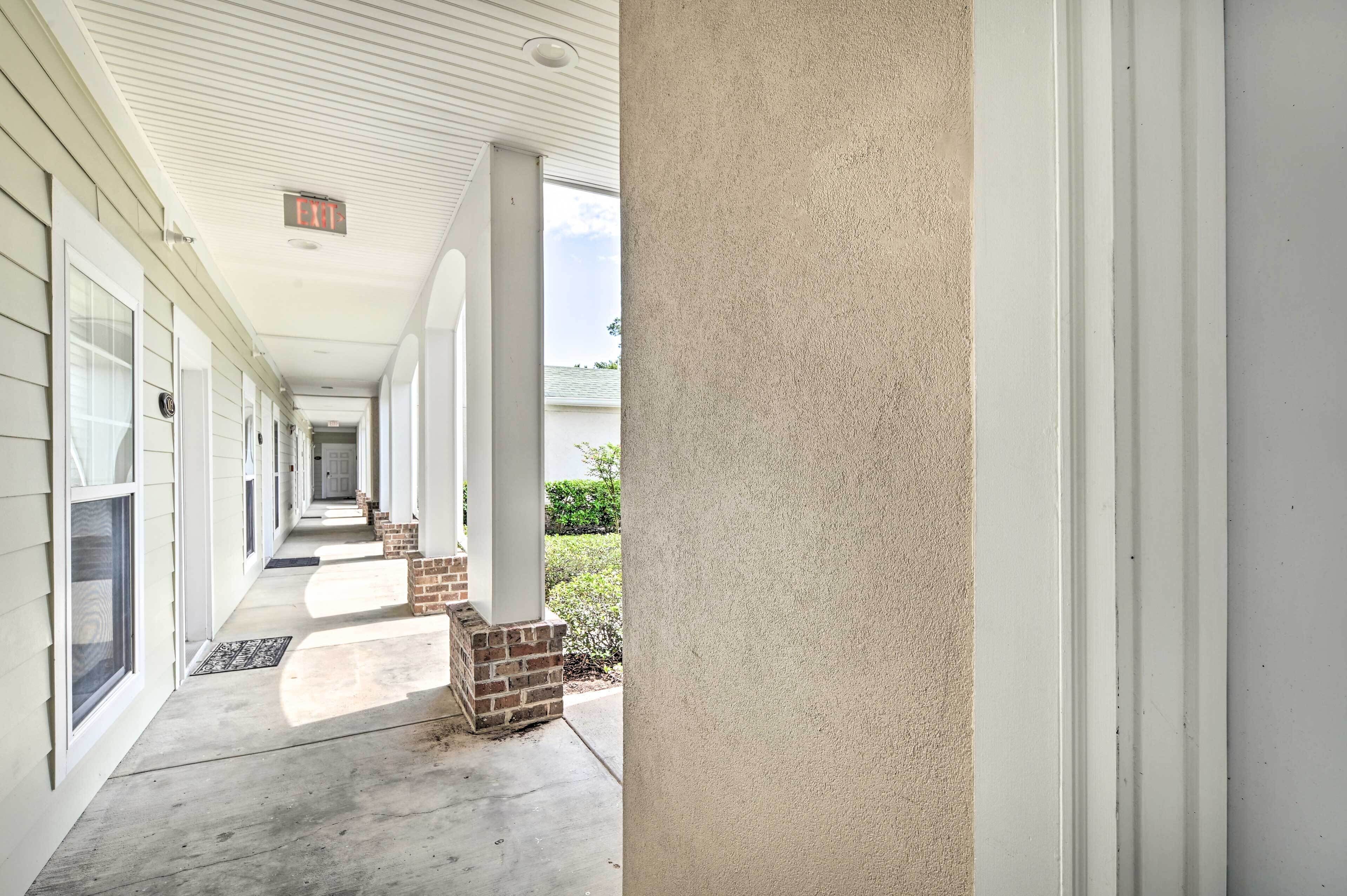 A covered corridor with brick pillars, a white ceiling, and a clear view of the sky.