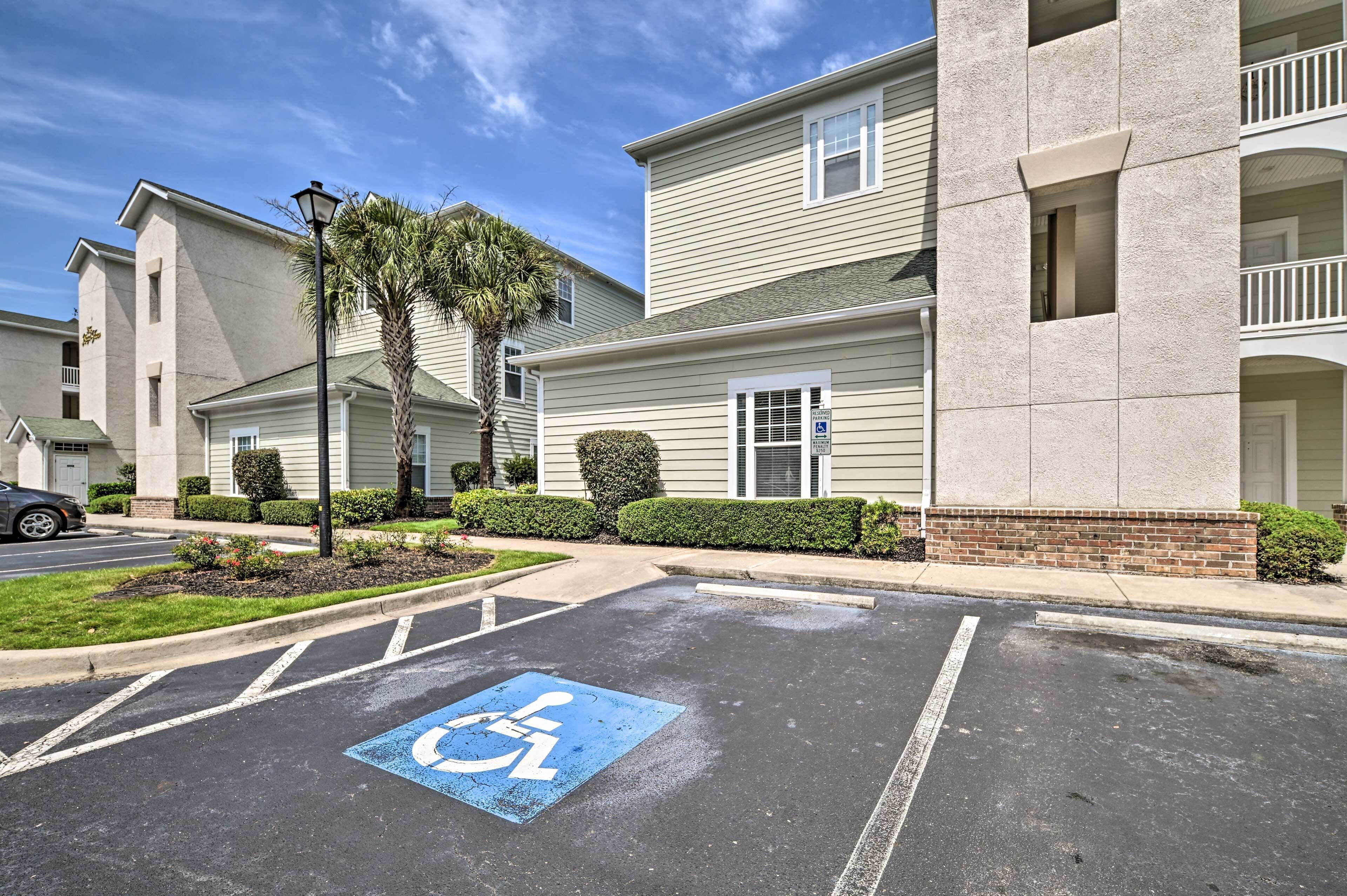 A parking lot with a handicapped parking space, a building with a brick base and beige siding, and a palm tree.