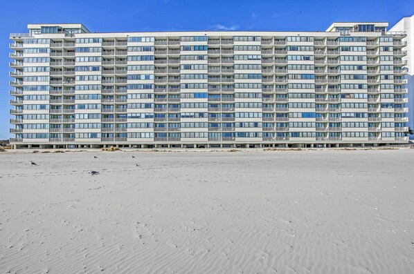 A high-rise hotel with multiple balconies and a sandy beach in the foreground. - 2 Mi to Golfing: Oceanfront Myrtle Beach Condo (Myrtle Beach)