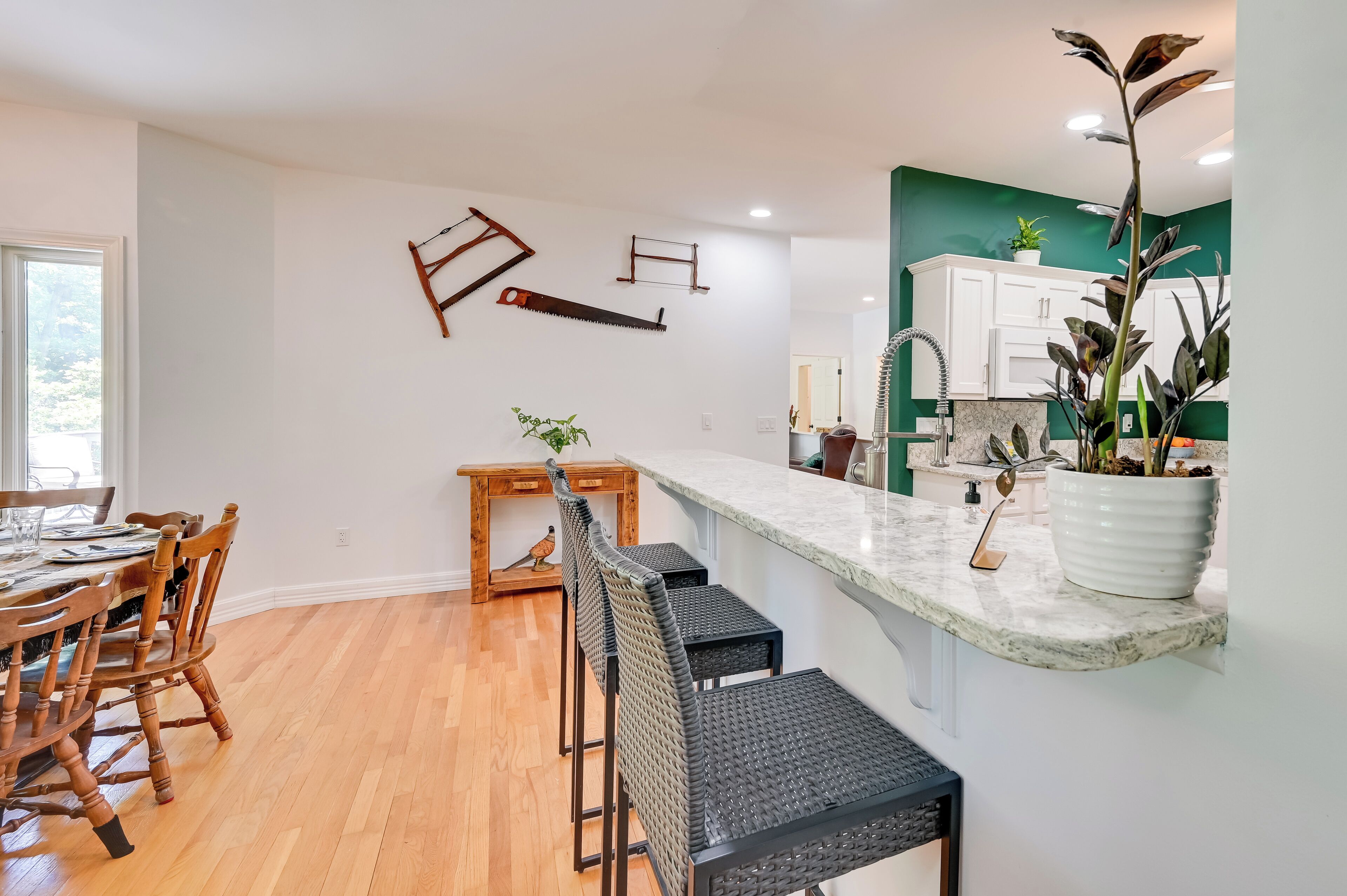 A modern kitchen with a marble countertop, wooden chairs, and a dining table.