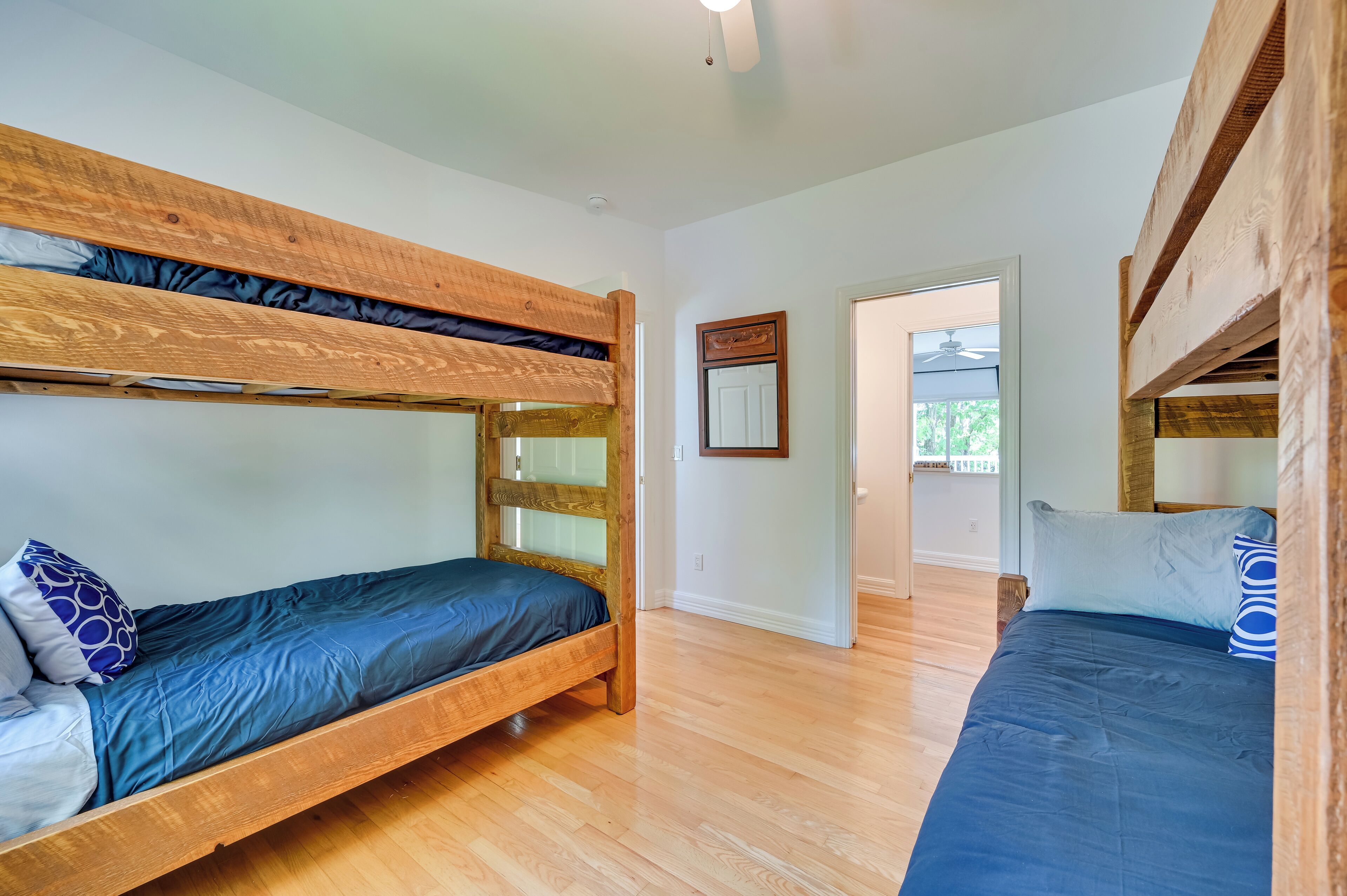 Une pièce avec deux lits superposés, un plancher en bois et une porte donnant sur un espace extérieur.
