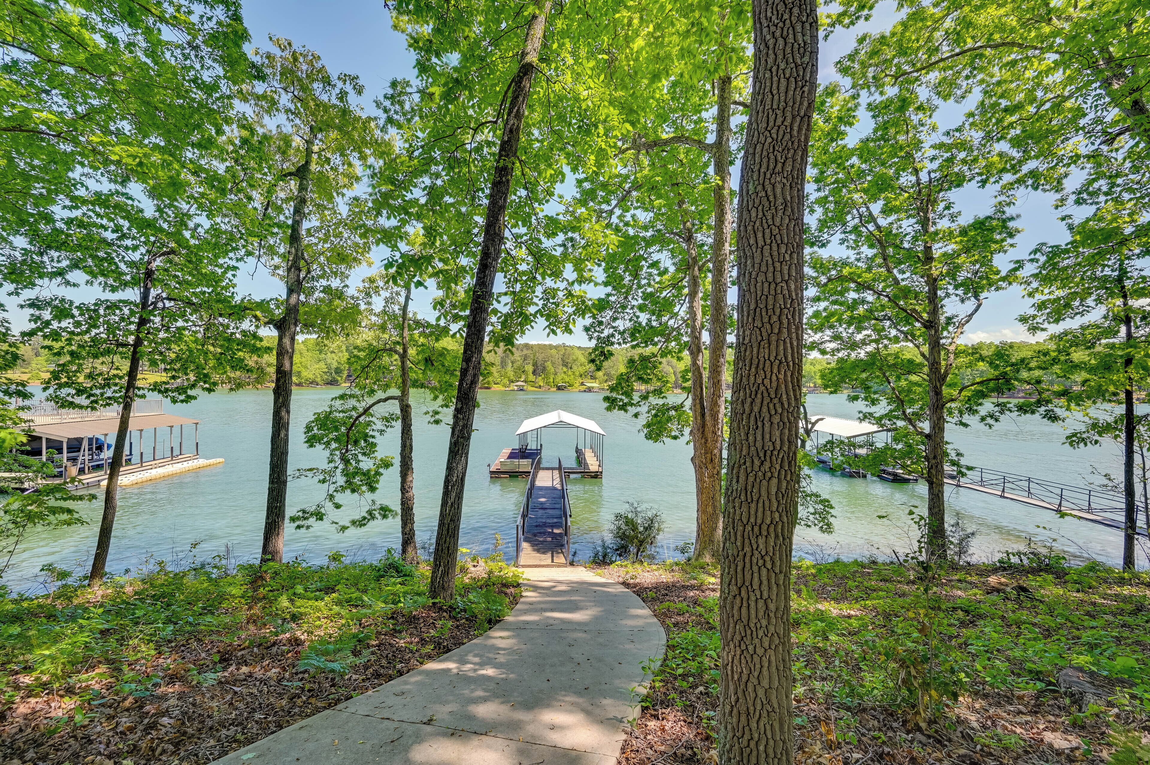 A lakeside walkway leading to a dock with a covered seating area.