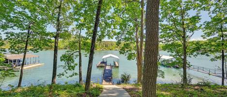 A lakeside walkway leading to a dock with a covered seating area.