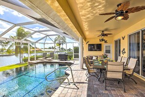 Relax by the pool surrounded by lush palm trees and a serene body of water.
