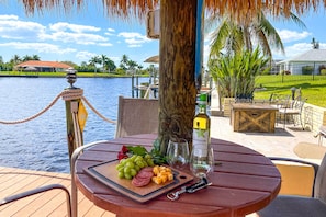 Enjoy a leisurely meal in a serene outdoor setting with a view of the water and well-manicured lawn.