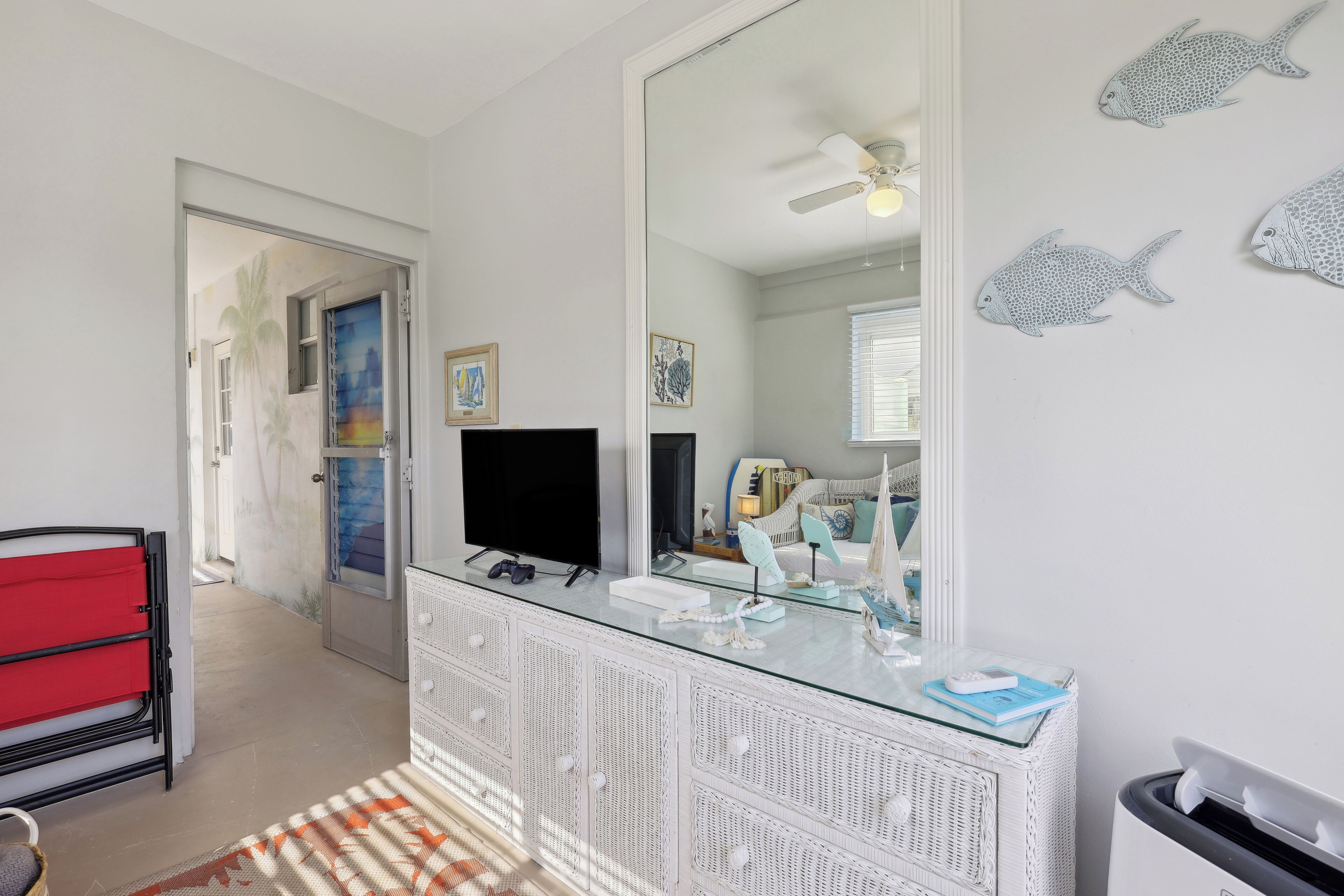 Un baño moderno con tocador de vidrio, un espejo grande y arte mural de peces decorativos.